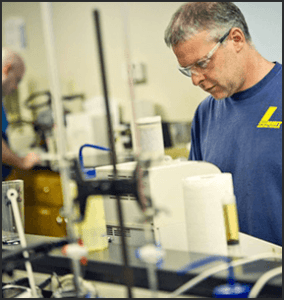 Summit Lubricant worker next to a machine