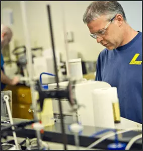 Summit Lubricant worker next to a machine